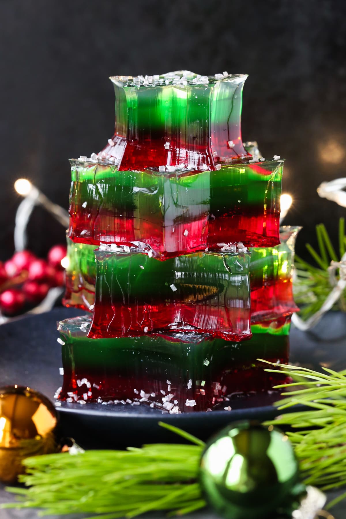 This Christmas Jello Dessert is going to be the star of the party! This festive dessert is made with a splash of real bubbly champagne! stacked jello shots with christmas decorations