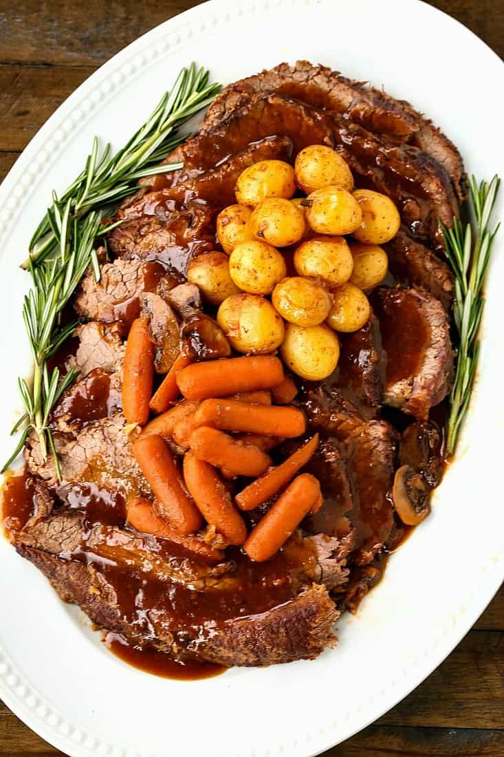Pot roast recipe on a platter with vegetables is a perfect sunday dinner
