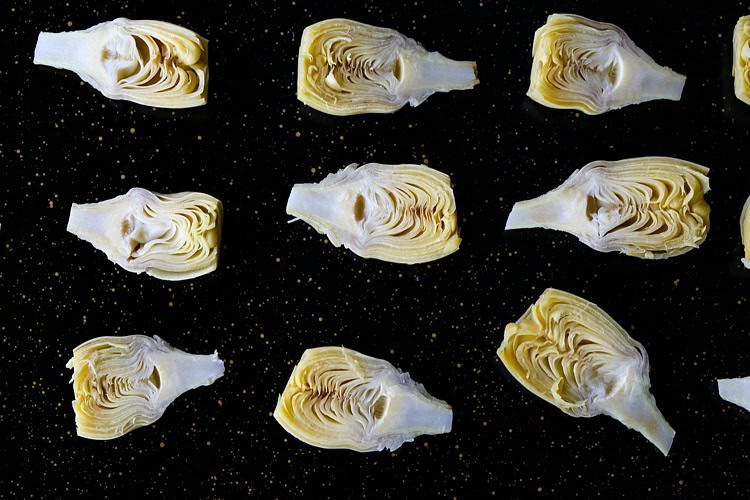 artichoke hearts cut in half on a baking sheet