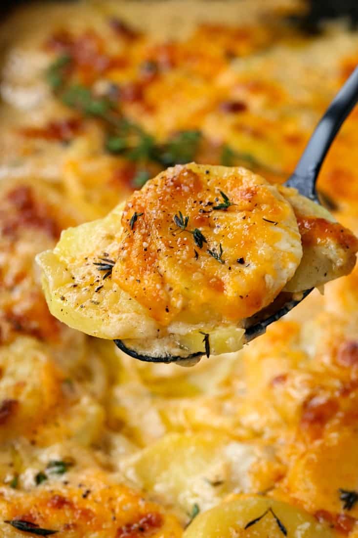 scalloped potatoes with a spoon of cheesy potatoes