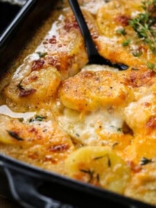 potato gratin in a black baking dish with a spoon