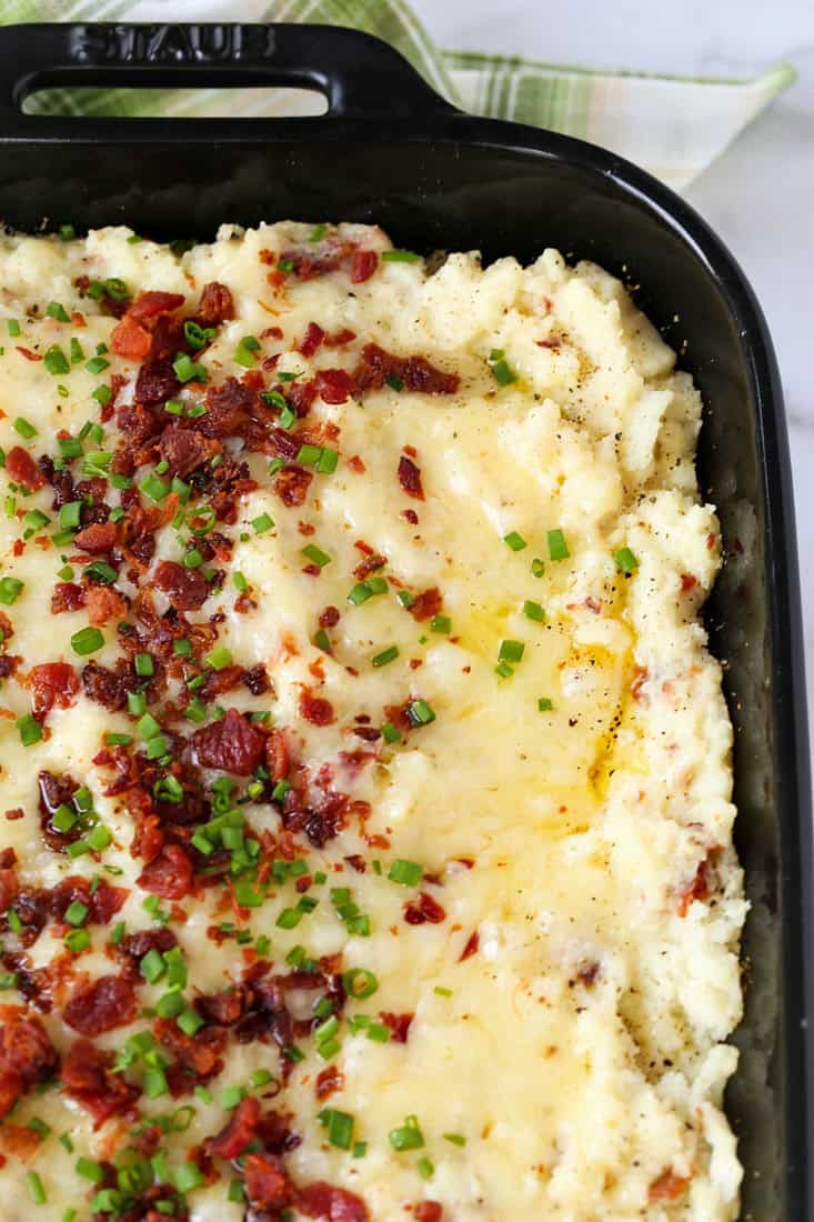 potato casserole recipe in a black baking dish with bacon and cheese