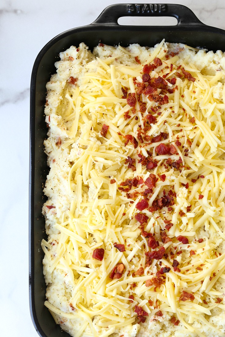 baked potato casserole topped with cheese and bacon in a black dish