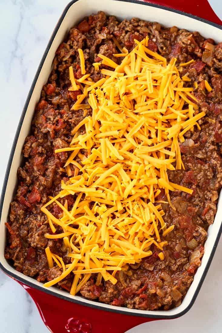 Cheeseburger casserole filling with shredded cheese on top