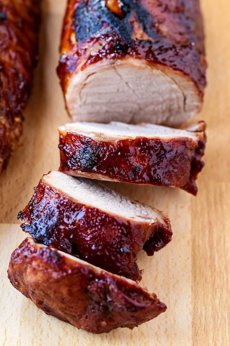 BBQ pork tenderloin sliced on a wooden board