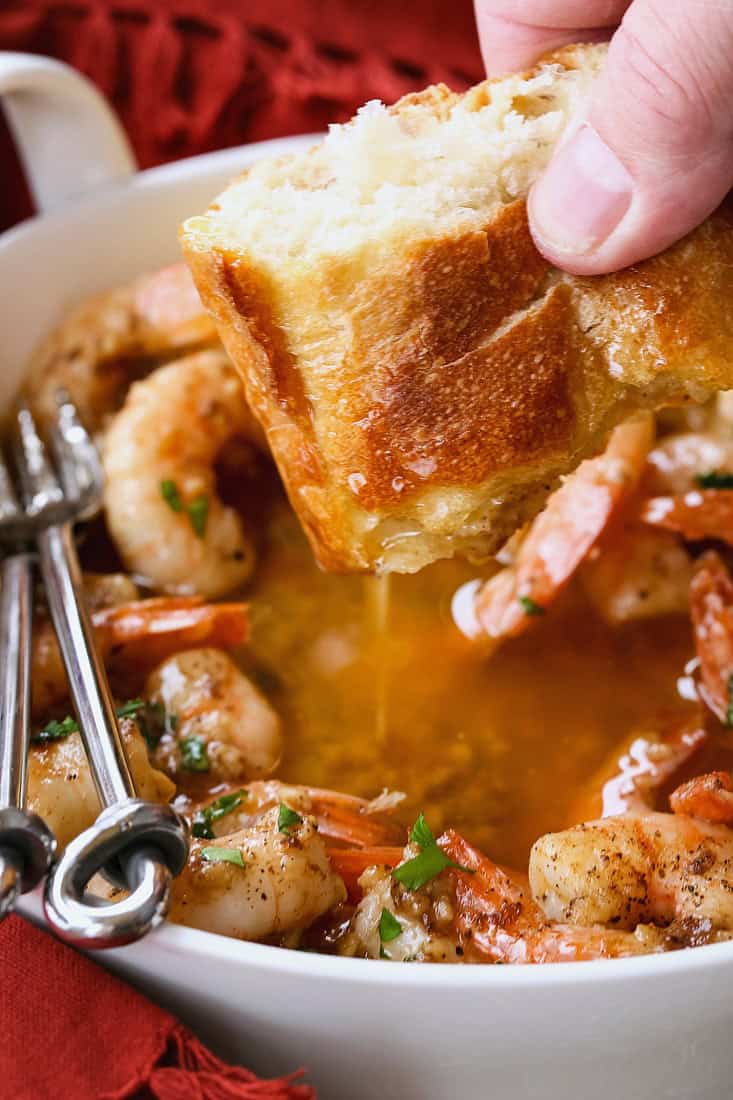 piece of bread being dipped into garlic butter sauce