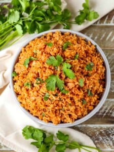 Spanish rice in a bowl with cilantro on a wood board