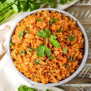 Spanish rice in a bowl with cilantro on a wood board