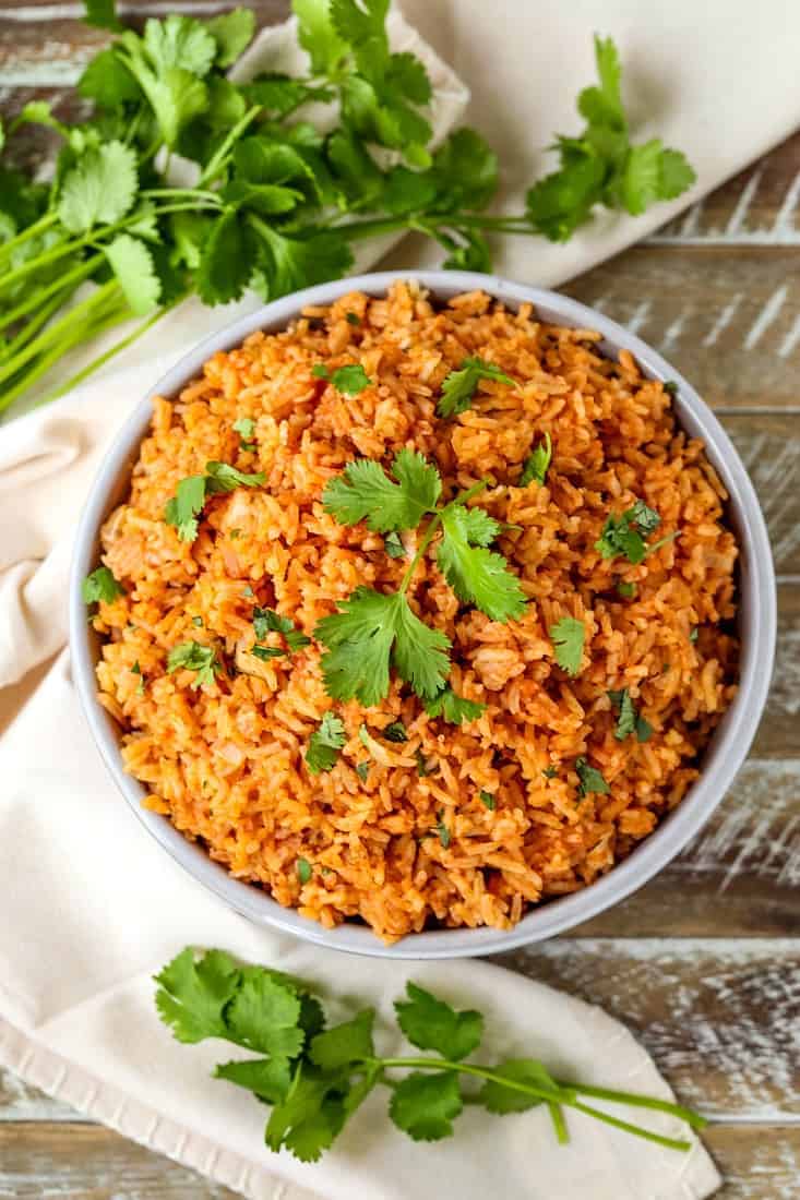 Spanish rice in a bowl with cilantro on a wood board 