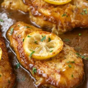 Chicken francese in a pan with a slice of lemon