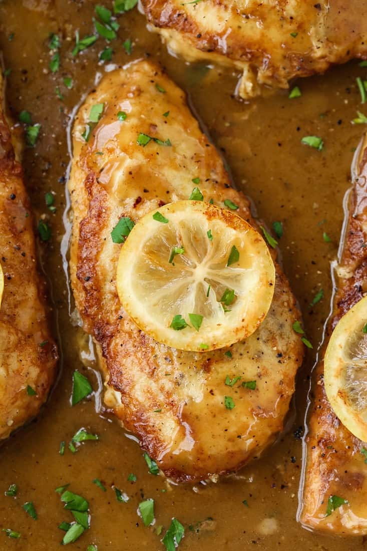 chicken breast cooked with lemon sauce and a lemon slice on top