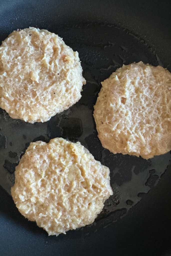 raw turkey burger patties in skillet