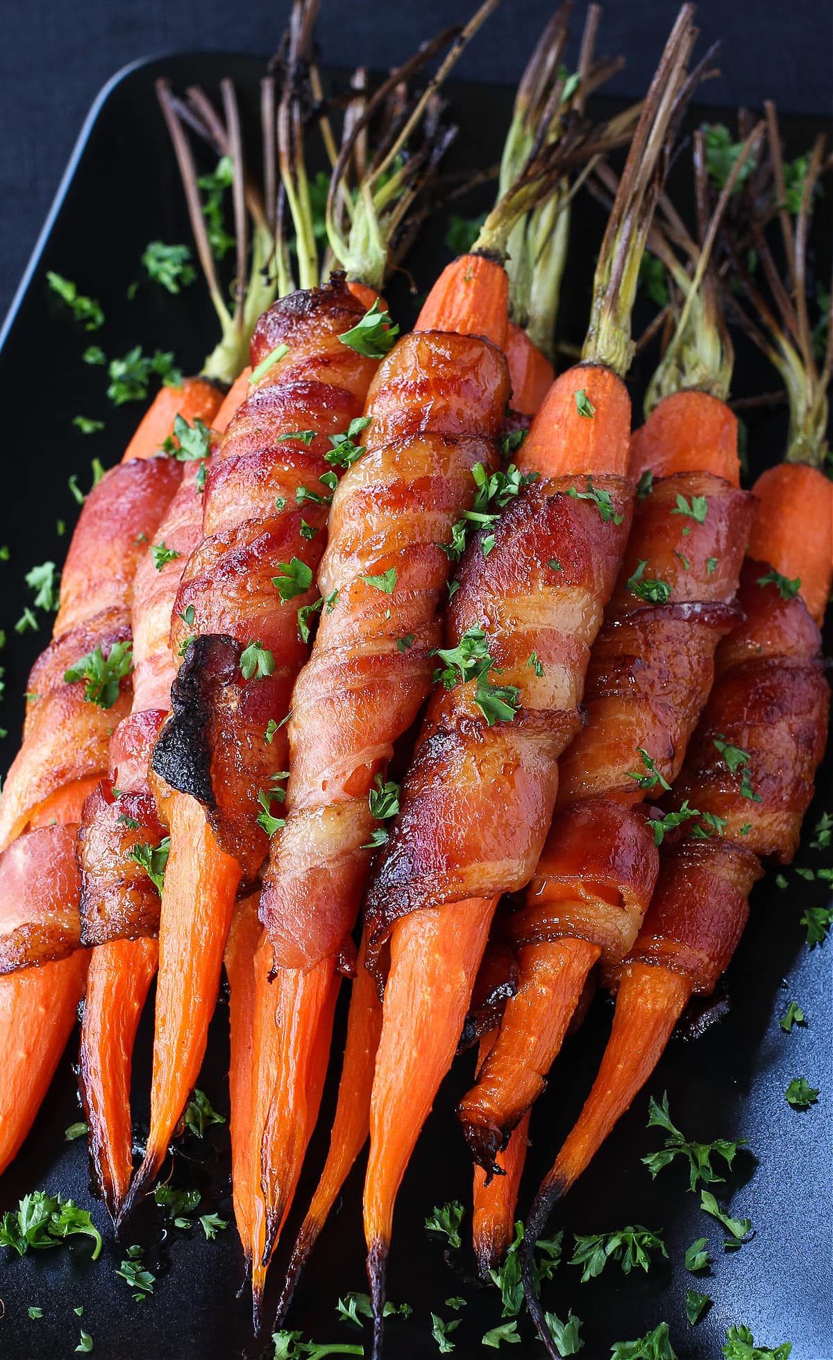 roasted carrots wrapped in bacon on black dish