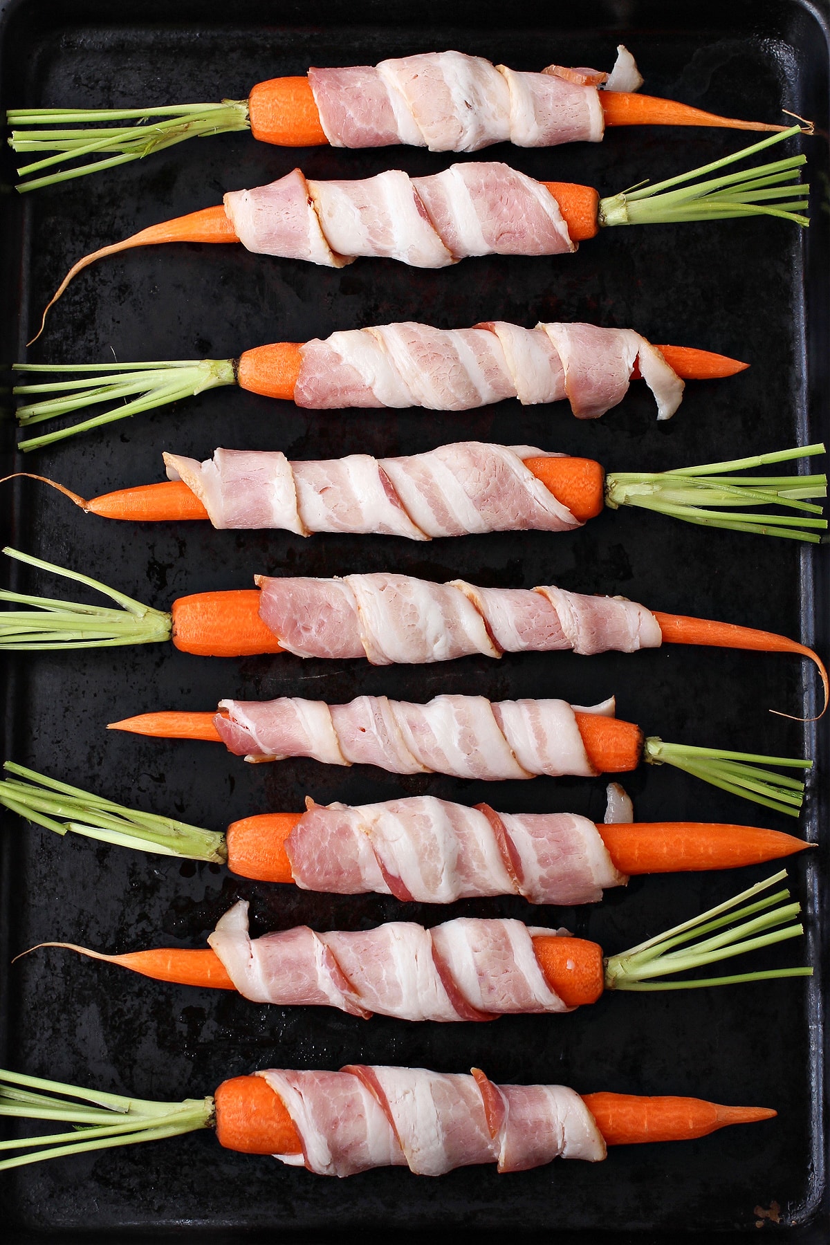bacon wrapped carrots on sheet pan before cooking
