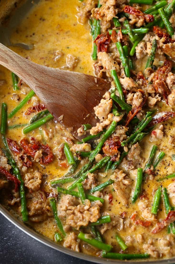 Sauce in skillet with sausage, asparagus and sun dried tomatoes for pasta recipe