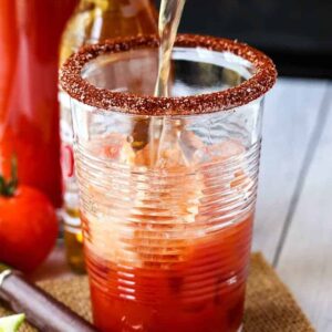 Beer pouring into a salt-rimmed glass to make a Michelada cocktail.