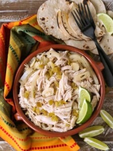 Shredded chicken in a bowl with limes