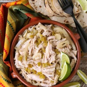 Shredded chicken in a bowl with limes