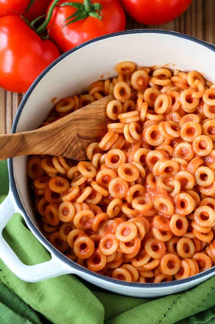 Spaghettios in a white pot with a wooden spoon