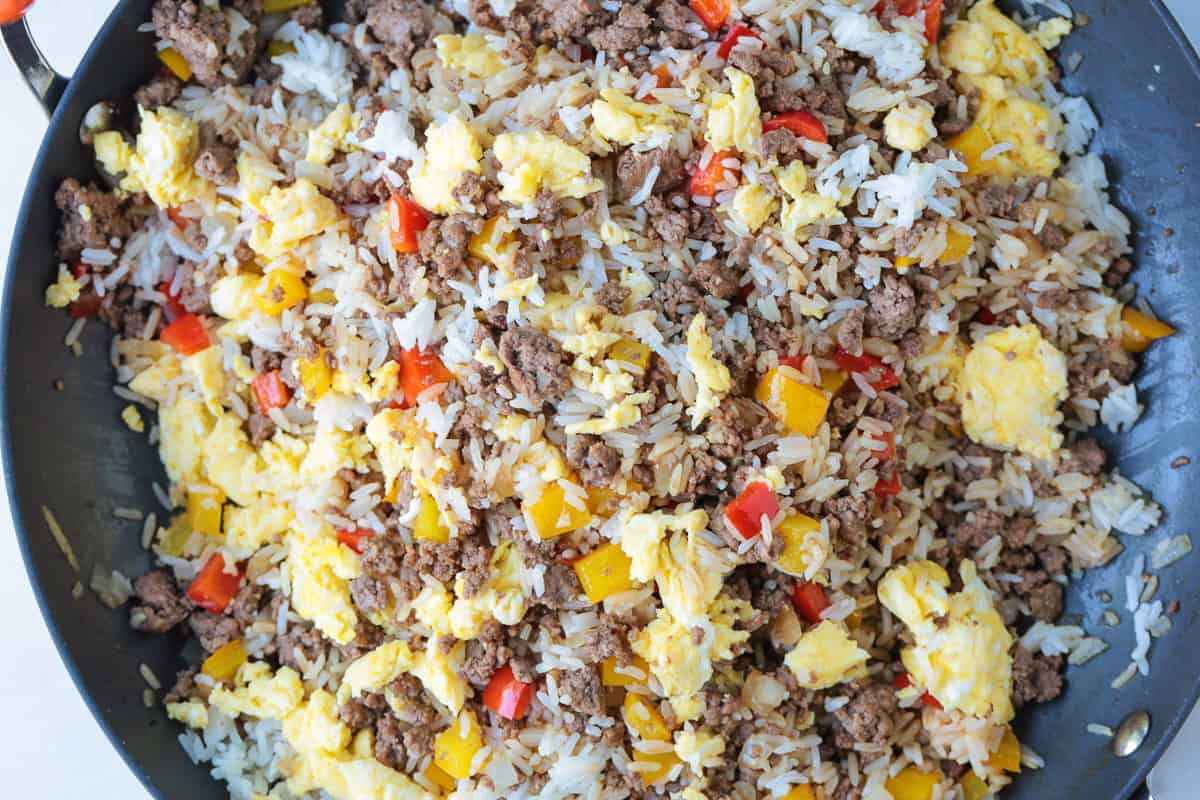 Philly Cheesesteak Fried Rice is the ultimate, comfort food dinner! Ground beef, peppers and gooey cheese make this fried rice irresistible! fried rice in skillet with ground beef, eggs, cheese and peppers