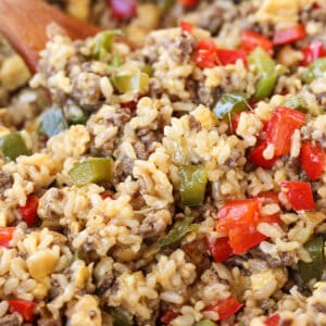 cheesy rice with ground beef and peppers in skillet with wooden spoon