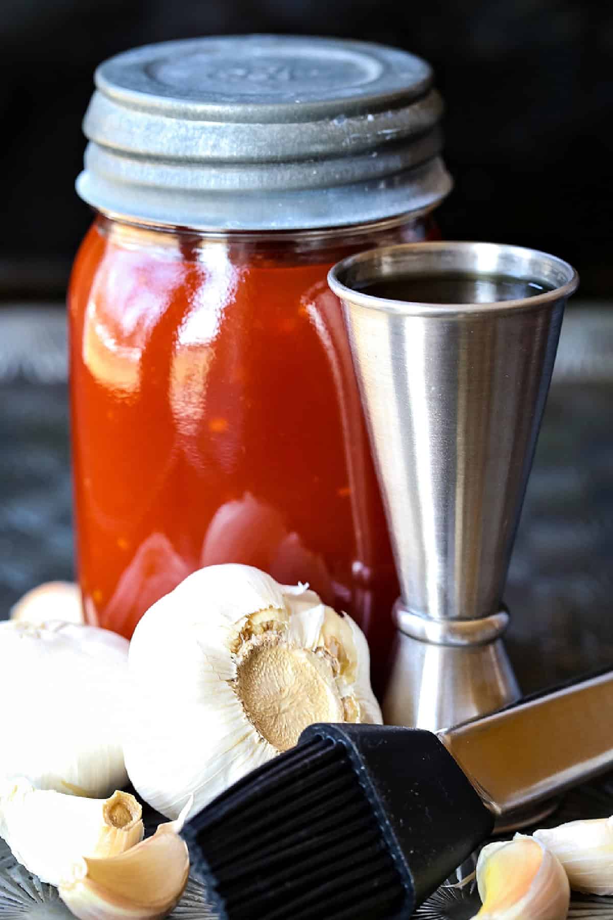 Our famous Whiskey Steak Marinade! Let this marinade work overnight for a tender, flavorful steak with a perfect caramelized crust! steak marinade in mason jar with garlic and whiskey