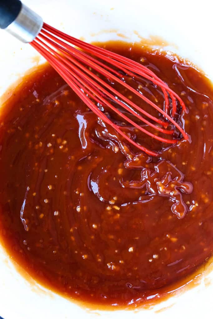 Our famous Whiskey Steak Marinade! Let this marinade work overnight for a tender, flavorful steak with a perfect caramelized crust! ketchup and whiskey marinade in bowl with whisk