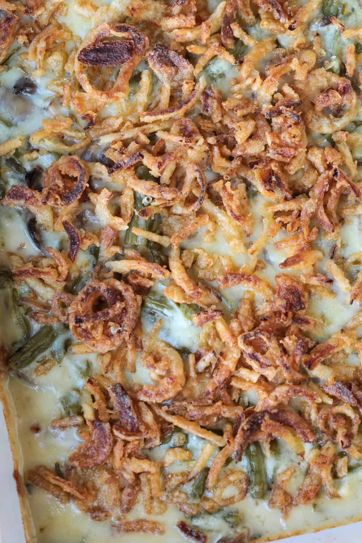 Cheesy Green Bean Casserole is sure to be a favorite Thanksgiving side dish! A scratch made cheesy cream sauce makes all the difference! close up of green bean casserole with fried onions