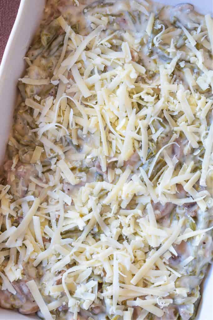 Cheesy Green Bean Casserole is sure to be a favorite Thanksgiving side dish! A scratch made cheesy cream sauce makes all the difference! casserole in baking dish with shredded cheese on top