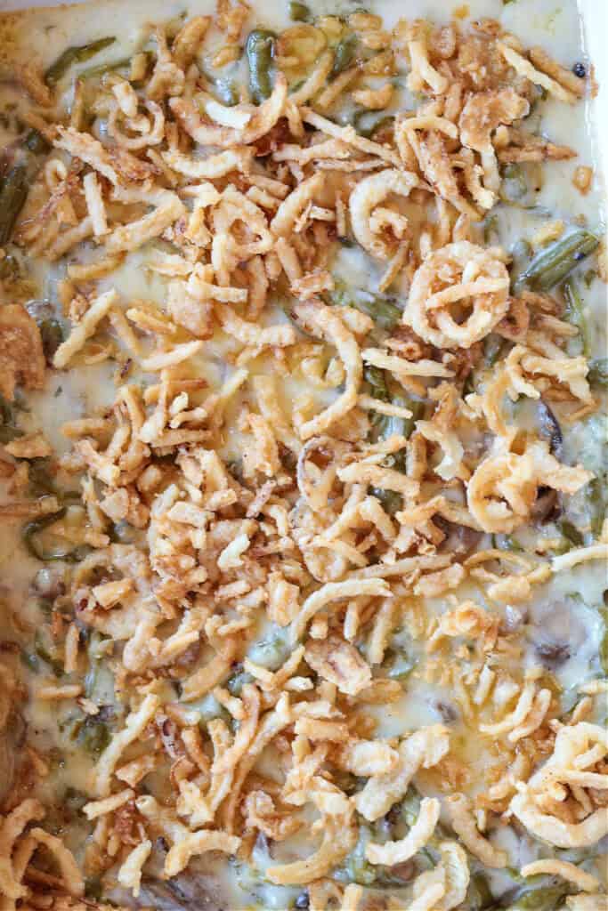Cheesy Green Bean Casserole is sure to be a favorite Thanksgiving side dish! A scratch made cheesy cream sauce makes all the difference! casserole in baking dish with fried onions on top