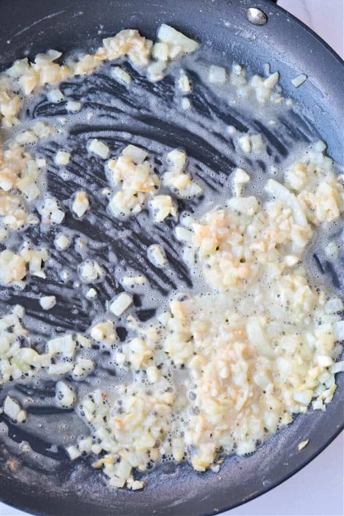 Cheesy Green Bean Casserole is sure to be a favorite Thanksgiving side dish! A scratch made cheesy cream sauce makes all the difference! onions in butter in a skillet with flour