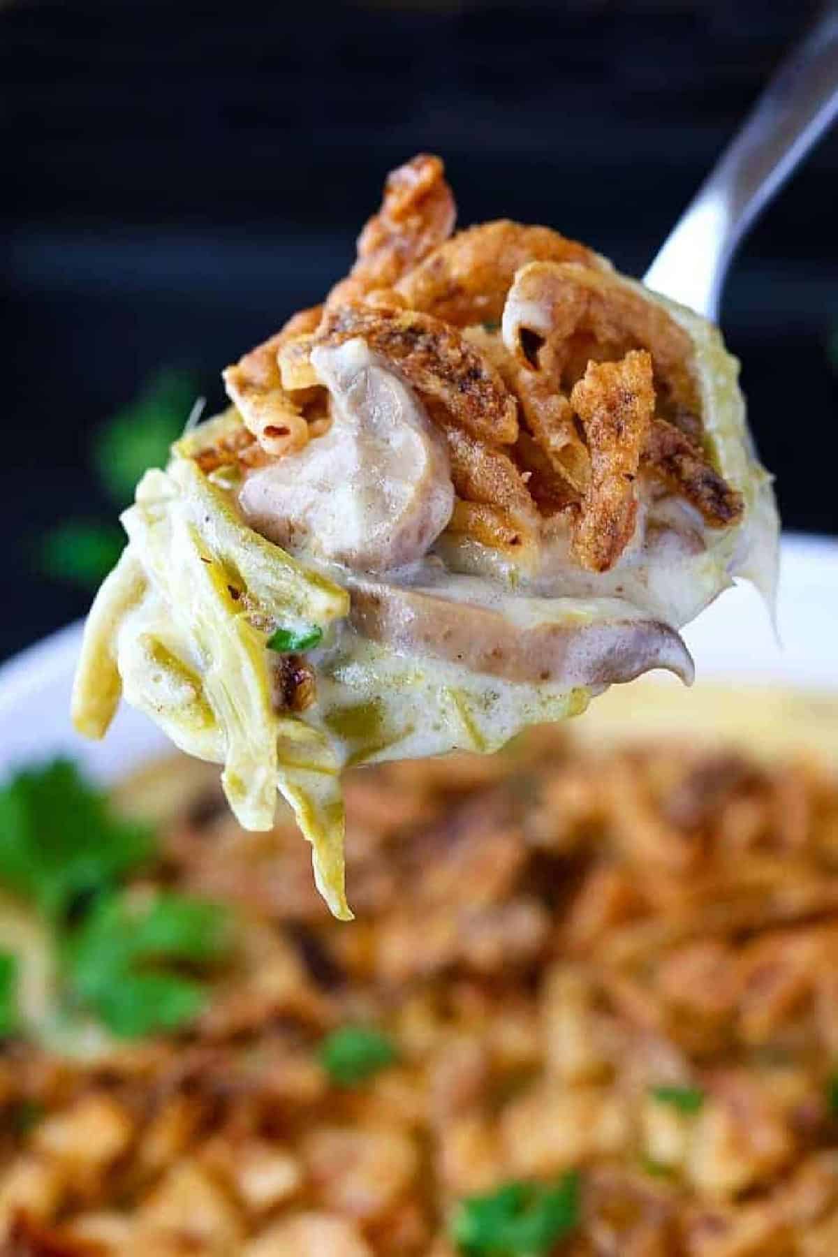 Cheesy Green Bean Casserole is sure to be a favorite Thanksgiving side dish! A scratch made cheesy cream sauce makes all the difference! green bean casserole on serving spoon
