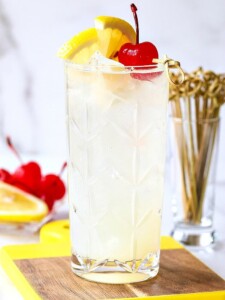 Tom Collins in a glass with lemon and cherry garnish