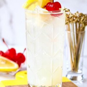 Tom Collins in a glass with lemon and cherry garnish