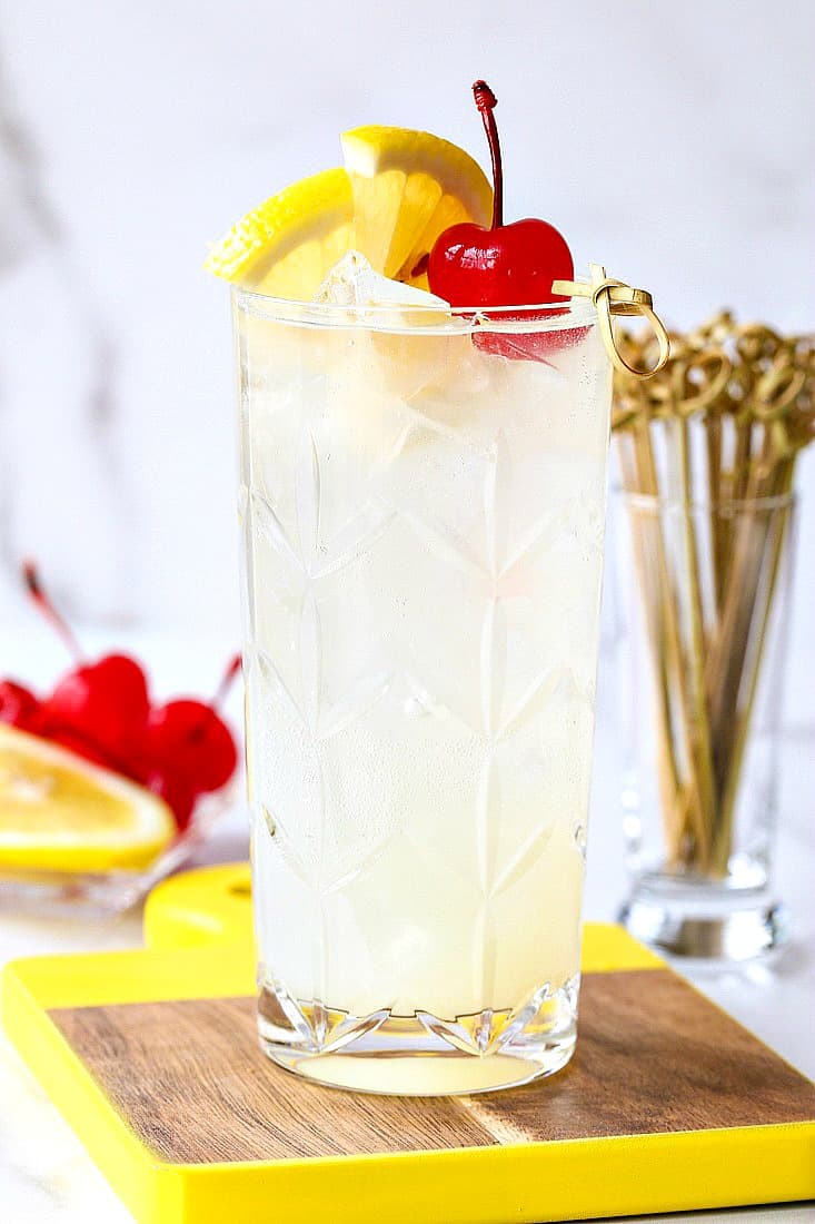 Tom Collins in a glass with lemon and cherry garnish