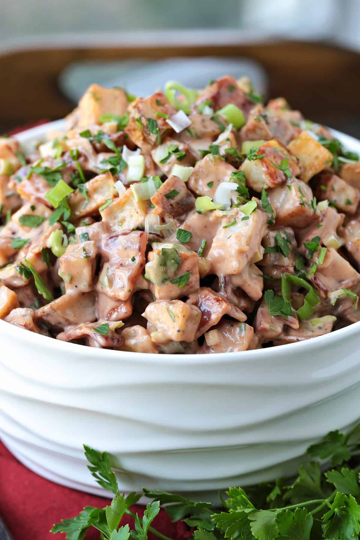 This Barbecue Roasted Potato Salad is unique side dish that everyone loves! Crispy, roasted potatoes tossed with a creamy, bbq dressing! bbq potato salad in a white bowl from the side