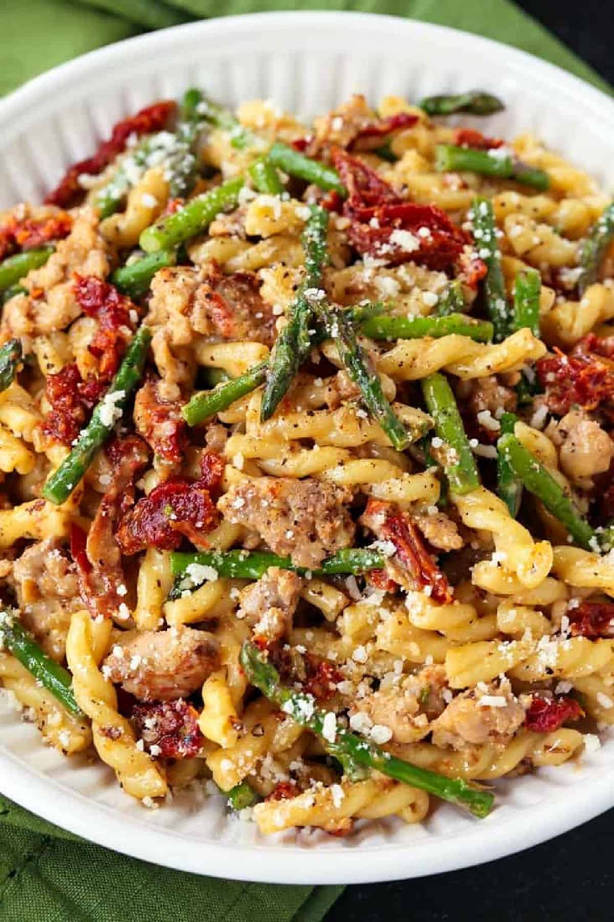 Gemelli with Sausage and Asparagus is light yet full of flavor. Zesty Italian sausage and crisp asparagus tossed in a light white wine sauce. pasta with sausage and asparagus in white bowl