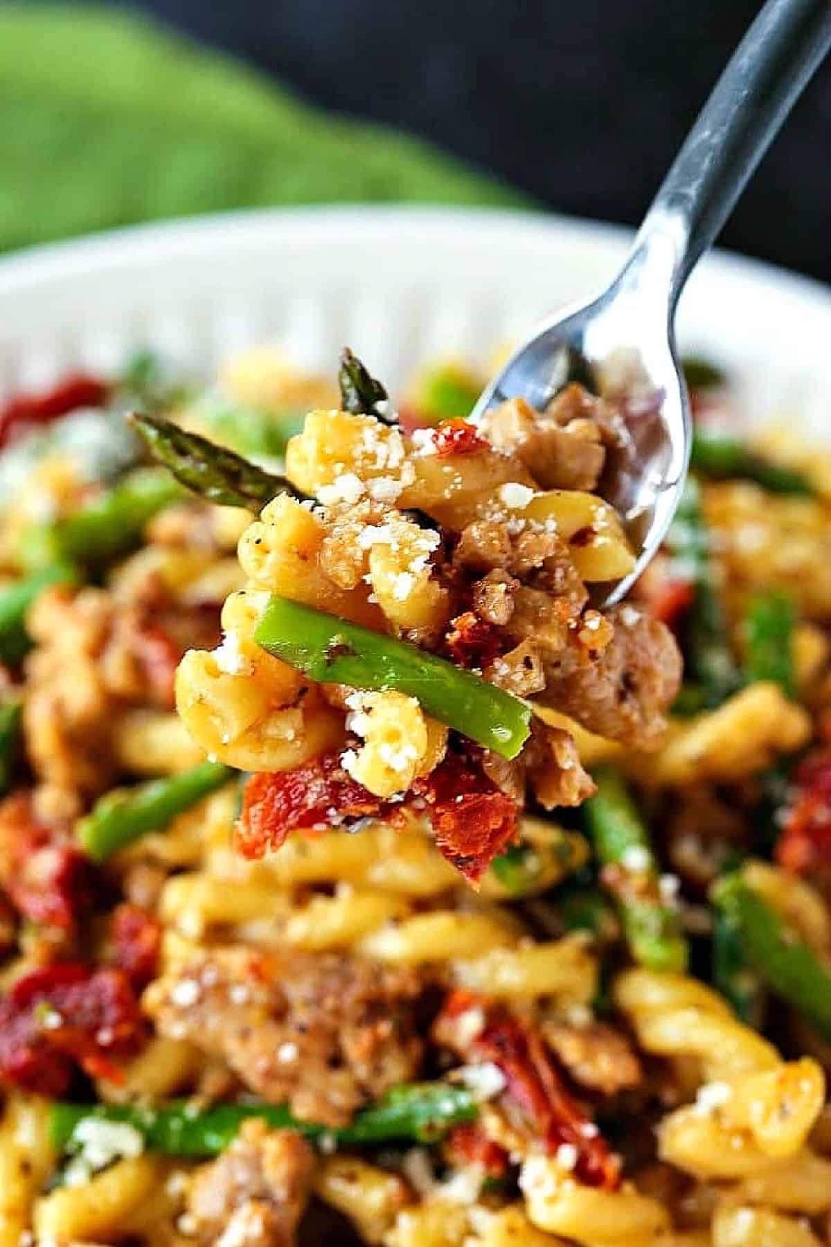 Gemelli with Sausage and Asparagus is light yet full of flavor. Zesty Italian sausage and crisp asparagus tossed in a light white wine sauce. pasta with sausage and asparagus on a fork