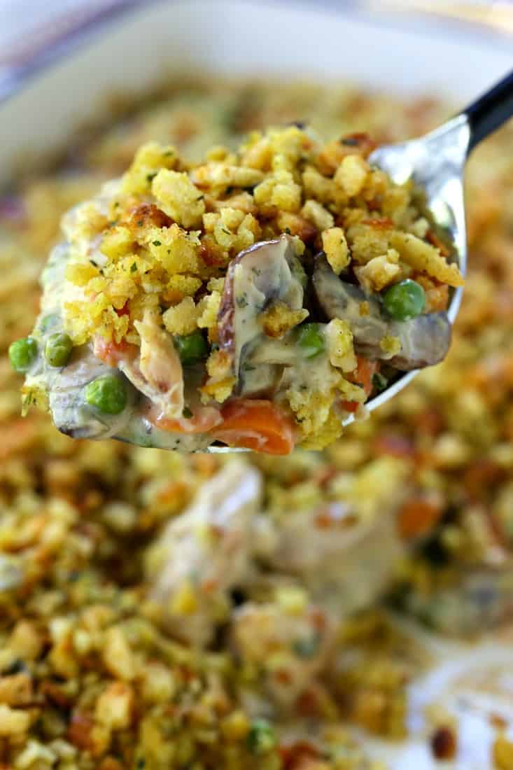 Chicken and Stuffing Casserole is an easy, comfort food dinner recipe. A creamy chicken and vegetable filling with a crispy stuffing topping! Chicken and Stuffing Casserole on a serving spoon