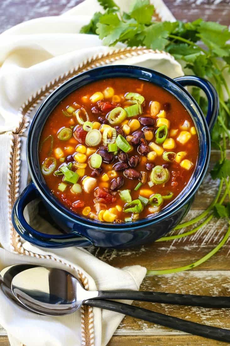 This Black Bean and Corn Soup is such an easy recipe! Your slow cooker does all the work for you, and blends the flavors together perfectly! Black bean soup in a soup bowl with cilantro