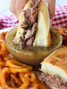 roast beef sandwich being dipped into au jus