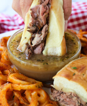 roast beef sandwich being dipped into au jus