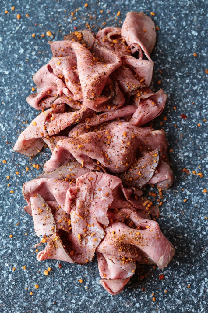 sliced roast beef on a board with seasoning