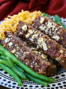 Slices of meatloaf stacked on a plate with green beans