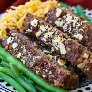 Slices of meatloaf stacked on a plate with green beans