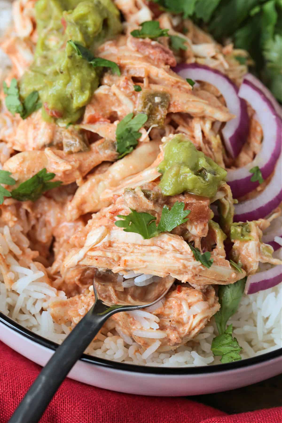 fork with salsa chicken and guacamole in rice bowl