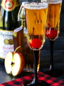 Apple cider cocktails with cherries and sparkling cider bottle