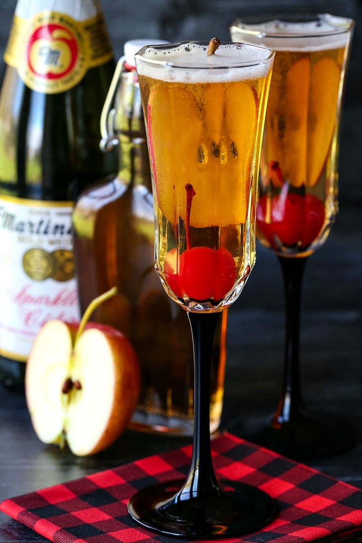 Apple cider cocktails with cherries and sparkling cider bottle