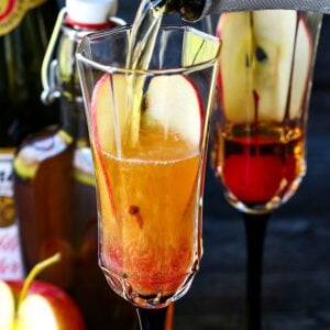 pouring sparkling cider into an apple cider cocktail