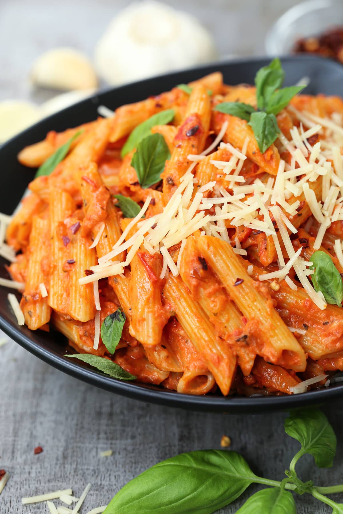 penne vodka in a black bowl with shredded parmesan cheese